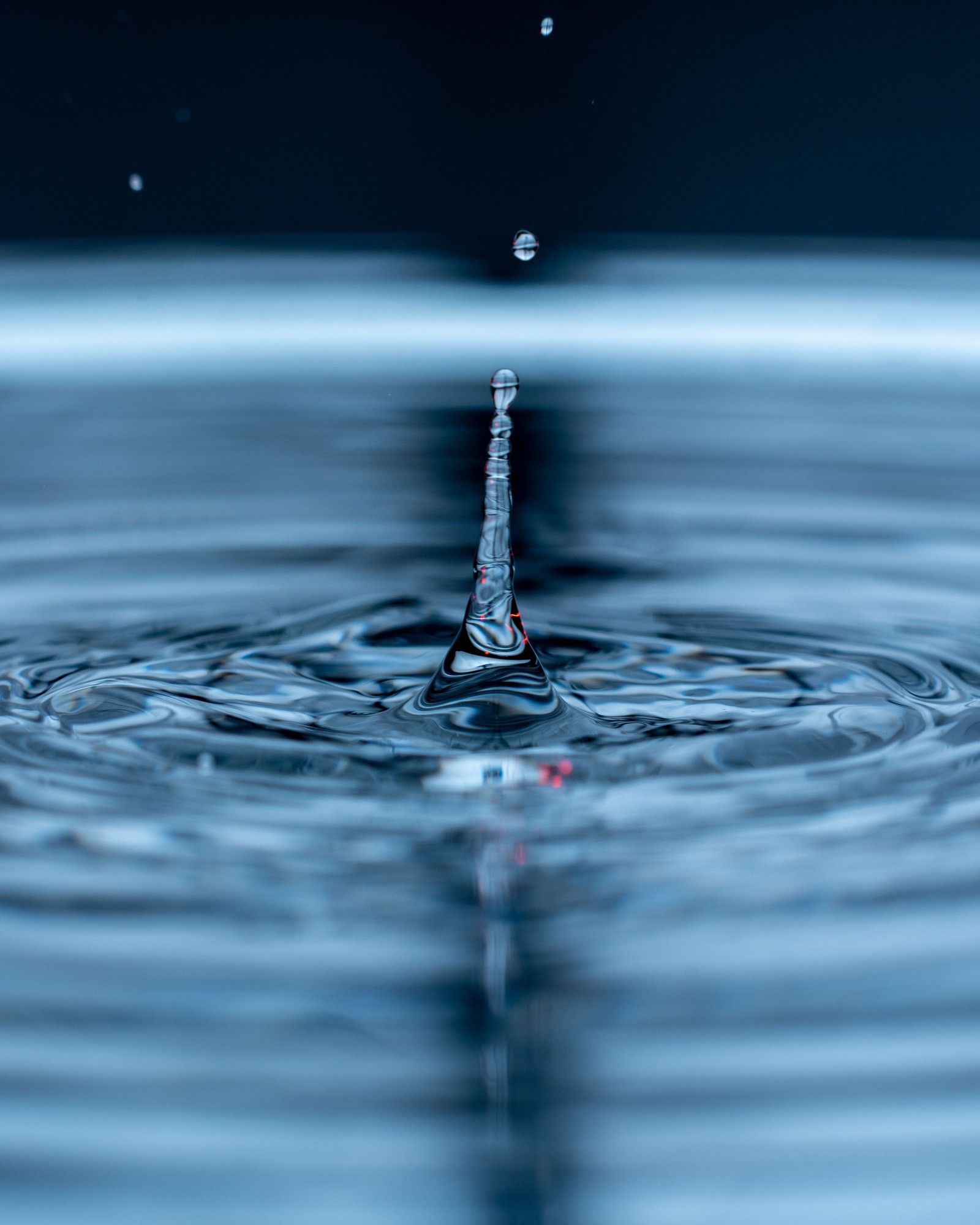 A drop of water falling into still blue water