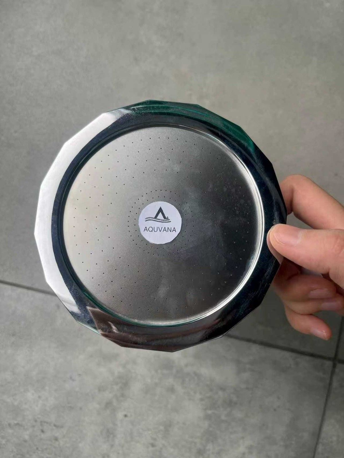 Aquvana shower head held in one hand